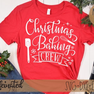 Pu&ograve; includere: Una maglietta rossa con la scritta bianca "Christmas Baking Crew". Il design include una spatola, una frusta, un fiocco di neve e uno striscione. La maglietta &egrave; esposta con jeans, verde e un'etichetta "Project Idea".