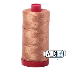 May include: A spool of Aurifil thread in a light peach color. The spool is wrapped in a red plastic cap and has a blue label with the Aurifil logo.
