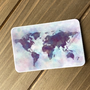 May include: A rectangular sticker featuring a watercolor world map design. The map is rendered in shades of purple, blue, and pink, with the text "@giftgratefulness" in the lower right corner. The sticker has a white border.