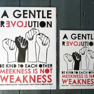 May include: Two black and white prints with the text "A Gentle Revolution" in black and "Be Kind To Each Other Meekness Is Not Weakness" in red. The prints feature a graphic of five raised fists.
