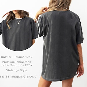 May include: A dark gray Comfort Colors 1717 t-shirt with a vintage style. The shirt is oversized and has short sleeves. The text on the image reads "Premium fabric than other T-shirt on ETSY" and "#1 ETSY TRENDING BRAND."