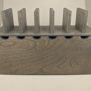 May include: A gray wooden box with six slots for storing items. The box has a lid and is made of wood with a natural grain.