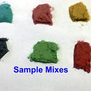 May include: Six small samples of colored sand, arranged in a row on a white surface. The colors are teal, red, yellow, dark blue, green, and red. The text "Sample Mixes" is written in blue letters below the samples.