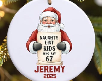 May include: A round Christmas ornament featuring Santa Claus holding a scroll. The scroll reads "NAUGHTY LIST KIDS WHO SAY 67 JEREMY 2025". Santa is wearing a red suit and hat with a white beard. The ornament has a string for hanging.