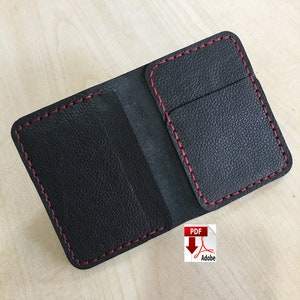 May include: Black leather wallet with red stitching and a single pocket on the inside. The wallet is open and lying flat on a wooden surface.