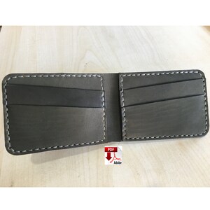May include: A brown leather wallet with multiple card slots and a billfold. The wallet is open and the inside is visible. The wallet has white stitching around the edges.