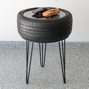 Bar-height tire table crafted from a real recycled tire, featuring a flush plexiglass top, solid wood base, and sturdy 24-inch metal legs, standing at 34 inches tall. This unique automotive table adds an industrial, modern touch to garages, man caves, bars, or home decor. Perfect as a high-top table, side table, or statement piece, it blends durability and style, making it a must-have for car lovers and those who appreciate repurposed furniture.