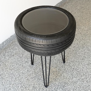 Bar-height tire table crafted from a real recycled tire, featuring a flush plexiglass top, solid wood base, and sturdy 24-inch metal legs, standing at 34 inches tall. This unique automotive table adds an industrial, modern touch to garages, man caves, bars, or home decor. Perfect as a high-top table, side table, or statement piece, it blends durability and style, making it a must-have for car lovers and those who appreciate repurposed furniture.
