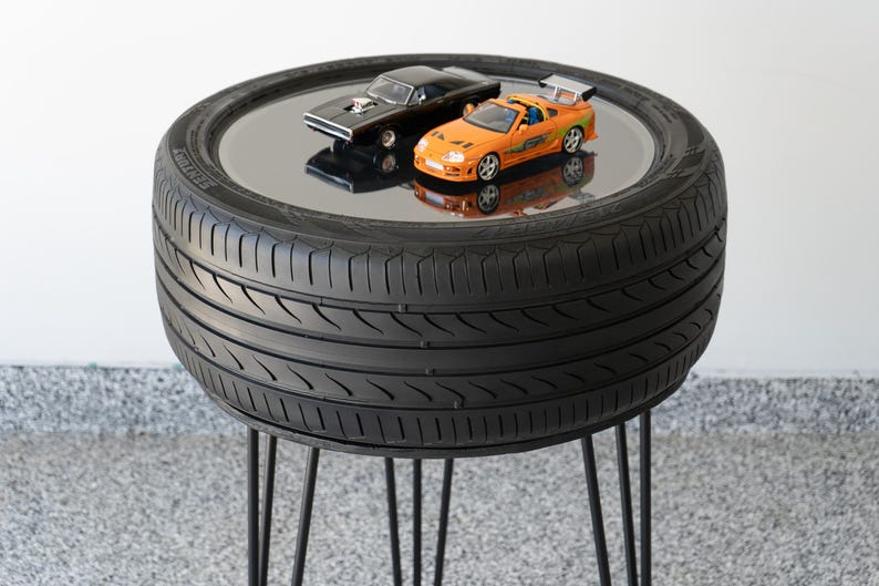 Bar-height tire table crafted from a real recycled tire, featuring a flush plexiglass top, solid wood base, and sturdy 24-inch metal legs, standing at 34 inches tall. This unique automotive table adds an industrial, modern touch to garages, man caves, bars, or home decor. Perfect as a high-top table, side table, or statement piece, it blends durability and style, making it a must-have for car lovers and those who appreciate repurposed furniture.
