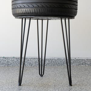 Bar-height tire table crafted from a real recycled tire, featuring a flush plexiglass top, solid wood base, and sturdy 24-inch metal legs, standing at 34 inches tall. This unique automotive table adds an industrial, modern touch to garages, man caves, bars, or home decor. Perfect as a high-top table, side table, or statement piece, it blends durability and style, making it a must-have for car lovers and those who appreciate repurposed furniture.