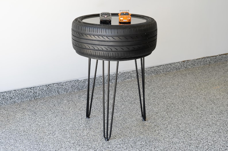 Bar-height tire table crafted from a real recycled tire, featuring a flush plexiglass top, solid wood base, and sturdy 24-inch metal legs, standing at 34 inches tall. This unique automotive table adds an industrial, modern touch to garages, man caves, bars, or home decor. Perfect as a high-top table, side table, or statement piece, it blends durability and style, making it a must-have for car lovers and those who appreciate repurposed furniture.