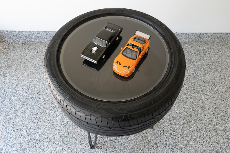 Bar-height tire table crafted from a real recycled tire, featuring a flush plexiglass top, solid wood base, and sturdy 24-inch metal legs, standing at 34 inches tall. This unique automotive table adds an industrial, modern touch to garages, man caves, bars, or home decor. Perfect as a high-top table, side table, or statement piece, it blends durability and style, making it a must-have for car lovers and those who appreciate repurposed furniture.