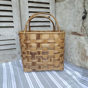 May include: A woven brown and tan rectangular basket with two brown handles. The basket is made of natural materials and has a rustic look.