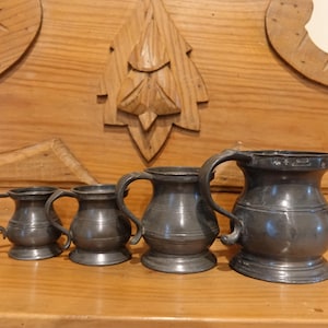 Könnte beinhalten: Eine weiße Keramik-Tasse mit schwarzem Henkel und dem Text "But First, Coffee" in fetter, schwarzer Schrift. Die Tasse steht vor einem verschwommenen Hintergrund, der eine gemütliche Umgebung andeutet.