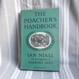 Op de afbeelding: Een groen boek getiteld "The Poacher's Handbook" door Ian Niall met houtsneden van Barbara Greg. De omslag van het boek toont een zwart-witte illustratie van een konijn in een nest van gras.