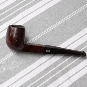 May include: A brown and black wooden pipe with a black mouthpiece and the word "ROPP" printed on the side.