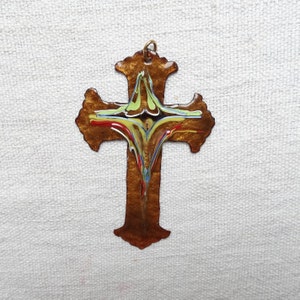 Peut inclure: Une croix en métal brun avec un motif abstrait coloré au centre. La croix a une finition légèrement vieillie et une boucle en haut pour l'accrocher.