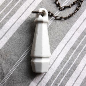 Puede incluir: Una taza de cerámica blanca con un asa negra y el texto "But First, Coffee" en un estilo manuscrito. La taza está sobre una superficie blanca. La taza mide aproximadamente 10 cm de alto.