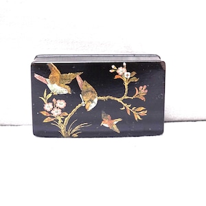 May include: A black rectangular box featuring a painted design of birds and flowers. The birds are depicted in shades of brown, orange, and white, set against a gold branch with pink and white blossoms. The box is likely made of wood.