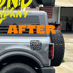 May include: Before and after images of a gray Ford Bronco with a black American flag decal on the rear window. The "Before" image shows the decal in place. The "After" image shows the decal replaced with a black and white leopard print decal. The text "DIAMOND VINYL COMPANY" is visible in yellow in the image.