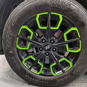 May include: A black car tire with a green rim. The tire has the words "CRUGEN HP71" and "KUMHO" printed on the side.