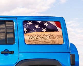 Könnte beinhalten: Ein blauer Jeep Wrangler mit einem "We the People" Aufkleber auf der Heckscheibe. Der Aufkleber zeigt die amerikanische Flagge und den Präambel der Verfassung der Vereinigten Staaten.