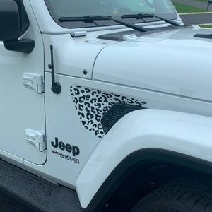 May include: White Jeep Wrangler with a black and white leopard print decal on the fender.