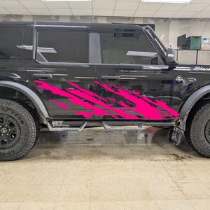 May include: Black SUV with large off-road tires and a pink splash design on the side. The text "Black Beauty" is visible on the front. The vehicle has a step bar and tinted windows.