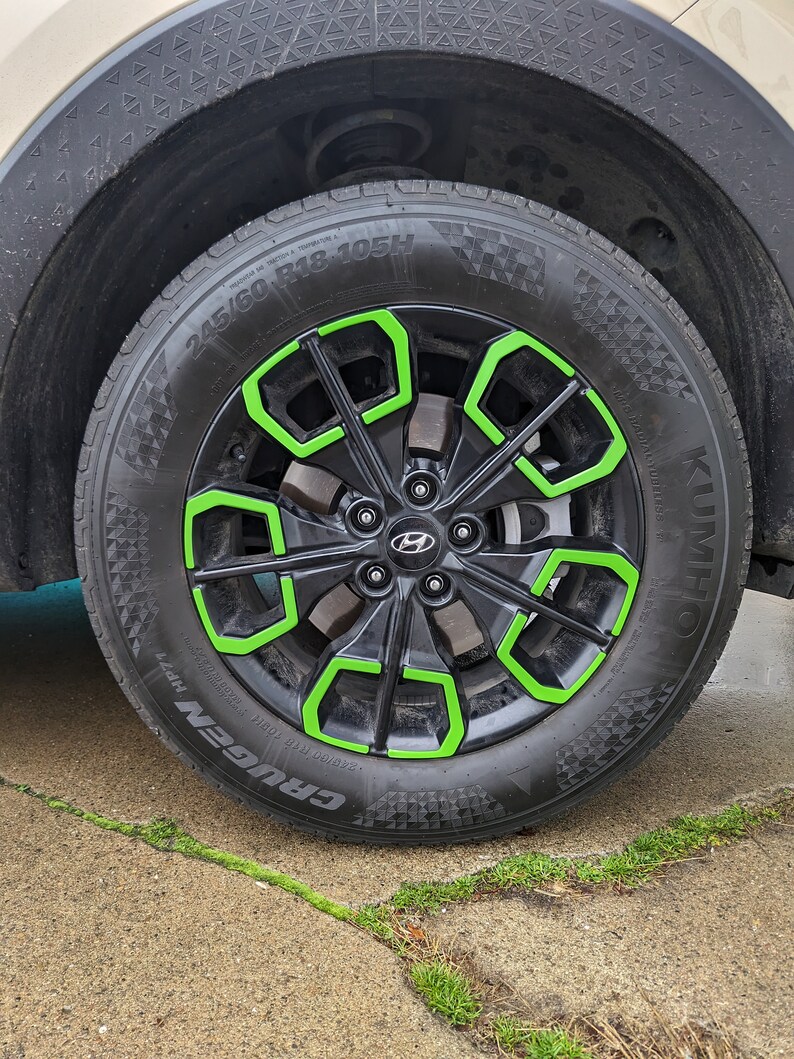 May include: A black car tire with a green rim and the words "CRUGEN HP71" and "KUMHO" printed on the side. The tire size is 245/60 R18-105H.