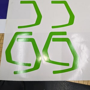 May include: Four green vinyl stickers in the shape of a stylized letter 'G' on a white background.