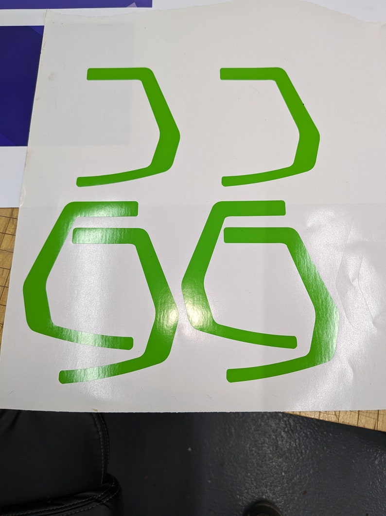 May include: Four green vinyl stickers in the shape of a stylized letter 'G' on a white background.