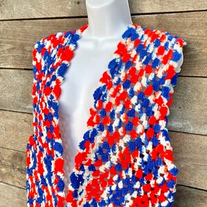 May include: A crocheted vest in red, white, and blue. The vest has a V-neck and is sleeveless.