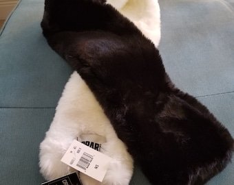 May include: A two-tone faux fur scarf in black and white. The scarf is soft and plush, with a label that reads "CREATED FOR MACY'S". The scarf is a stylish accessory for cold weather.