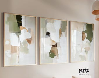 May include: Three abstract paintings in gold frames with a white, green, and brown color scheme. The paintings are hung on a light beige wall.