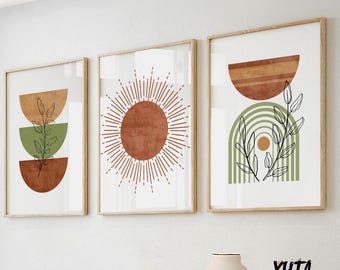Puede incluir: Tres impresiones artísticas enmarcadas con diseños abstractos. Las impresiones presentan colores tierra, incluyendo óxido, verde oliva y beige, con formas geométricas y elementos botánicos. Los marcos son de madera clara. El arte se exhibe en una pared blanca.