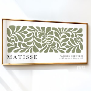 Könnte beinhalten: Ein gerahmter Kunstdruck mit einem goldenen Rahmen, der ein grünes Blattmuster auf weißem Hintergrund zeigt. Der Druck enthält den Namen "MATISSE" und den Text "PAPIERS DÉCOUPÉS du 27 février au 28 mars 1953".