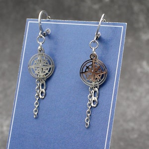 Op de afbeelding: Een paar zilveren oorbellen met een kompasontwerp en een hangende ketting. De oorbellen worden getoond op een blauwe kaart met de tekst "sopebbeads" in wit.