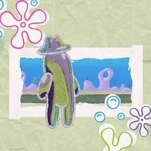 May include: Embroidered patch featuring a cartoon character in a fedora, with green, purple, and blue colors. The patch is set against a backdrop of an underwater scene, with decorative floral and bubble elements.