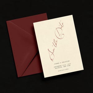 May include: A cream-colored invitation card with the words "Save the Date" in burgundy script, next to a burgundy envelope. The card includes the names Joanna & Christian, the date September 11th, 2026, and the location Brooklyn, New York.