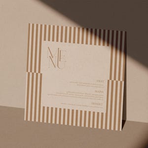 Puede incluir: Una tarjeta de menú cuadrada con fondo beige y rayas marrones verticales. La palabra "MENU" está en la parte superior, con texto debajo para "FIRST", "MAINS" y "DESSERT". La tarjeta está iluminada por una luz cálida.