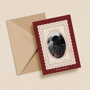 Könnte beinhalten: Eine bordeauxfarbene Hochzeitseinladung mit einem Foto eines sich küssenden Paares, umrahmt von einem weißen, spitzenartigen Rand. Die Einladung enthält die Namen "Abigail & Marco", das Datum "09.15.2024" und den Ort "New York, NY". Ein beigefarbener Umschlag liegt neben der Einladung.