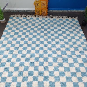 May include: A blue and white checkered rug with a fluffy texture. The rug has a fringe border.