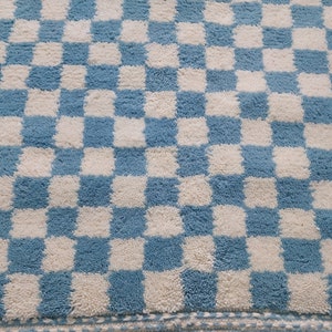 May include: A blue and white checkered bath mat with a fluffy texture.