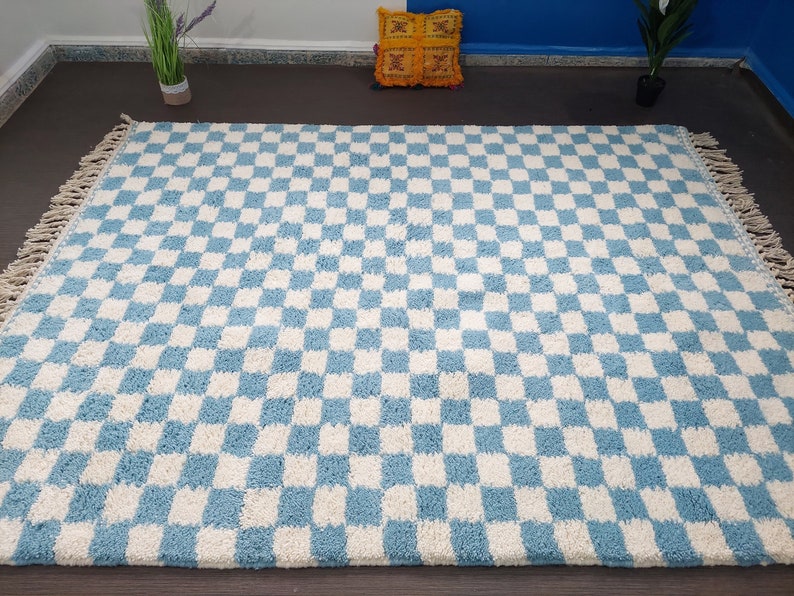 May include: A blue and white checkered rug with fringe on the edges. The rug is made of a soft, fluffy material.