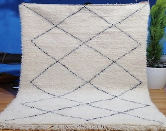 May include: White rug with a diamond pattern in black. The rug has a fringe border.