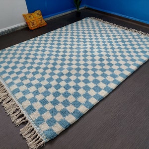 May include: A blue and white checkered rug with fringe edging. The rug is made of a soft, fluffy material.