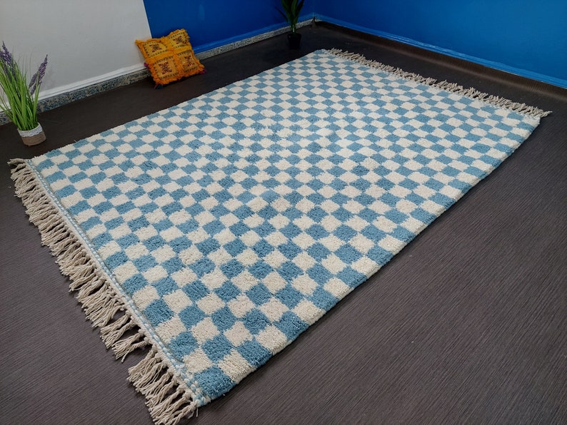 May include: A blue and white checkered rug with fringe edging. The rug is made of a soft, fluffy material.