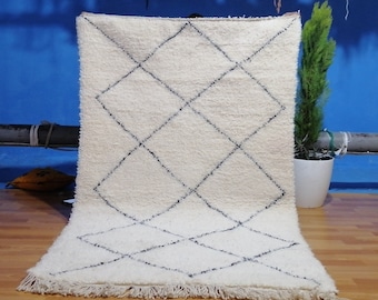 May include: White shag rug with a black diamond pattern. The rug has a fringe border.