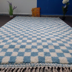May include: A blue and white checkered rug with a fringe border. The rug is made of a soft, fluffy material.