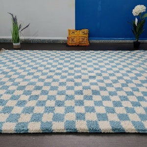May include: A blue and white checkered rug with fringe edges. The rug is made of a soft, fluffy material.